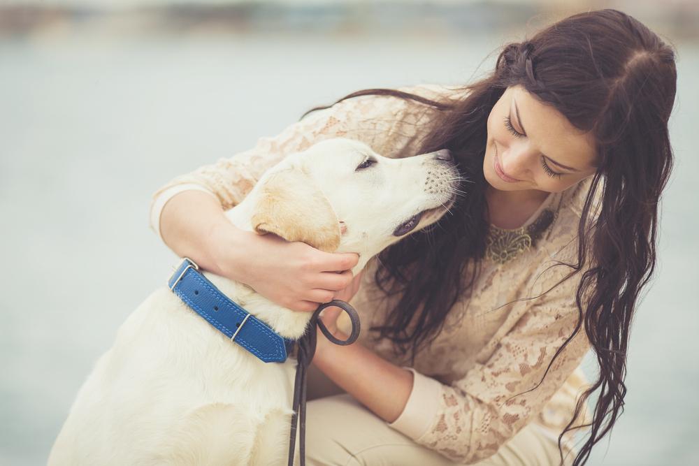 emotional support anima, esa. a young woman with long hair, hugging her golden retriever while smiling